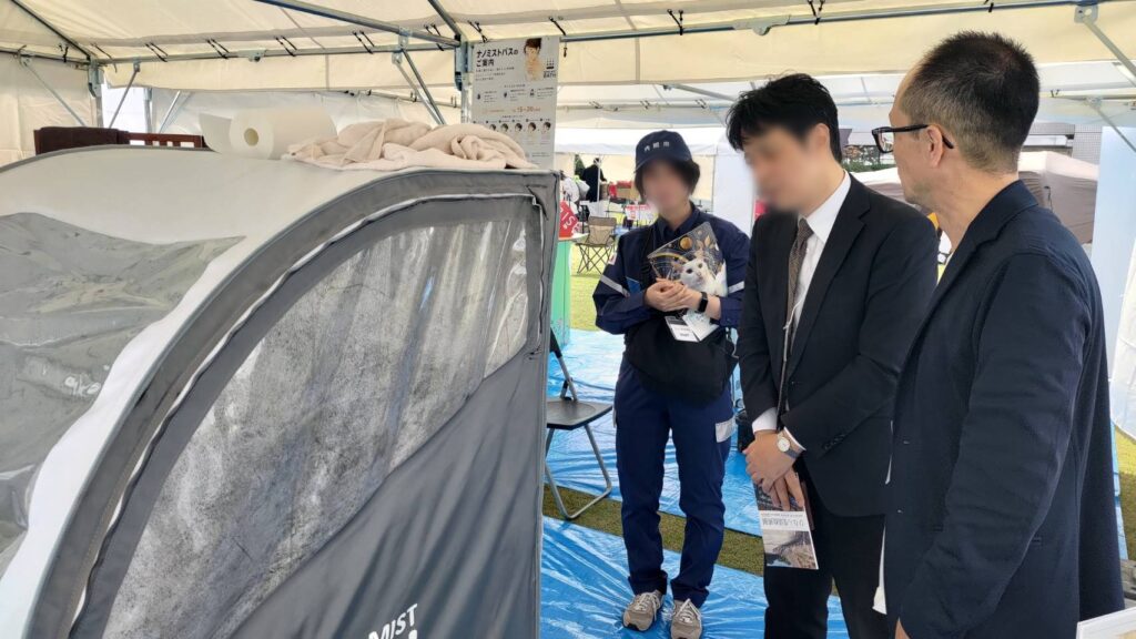 ナノミストバスの実機を前に説明を聞く来場者
